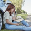 Women sitting beside car