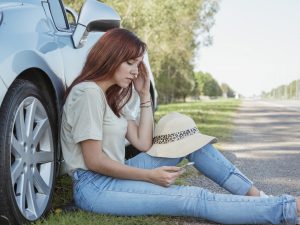 Women sitting beside car