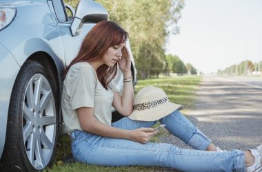 Women sitting beside car