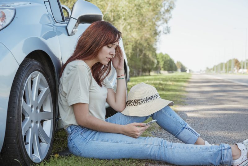 Women sitting beside car